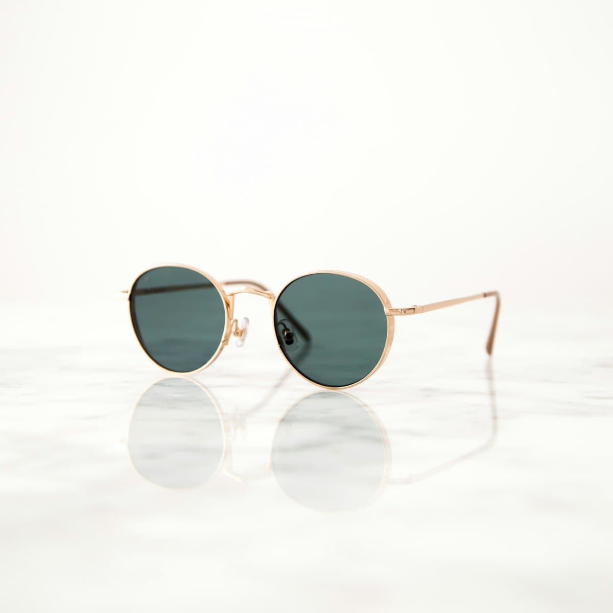 Gold-framed sunglasses resting on marble